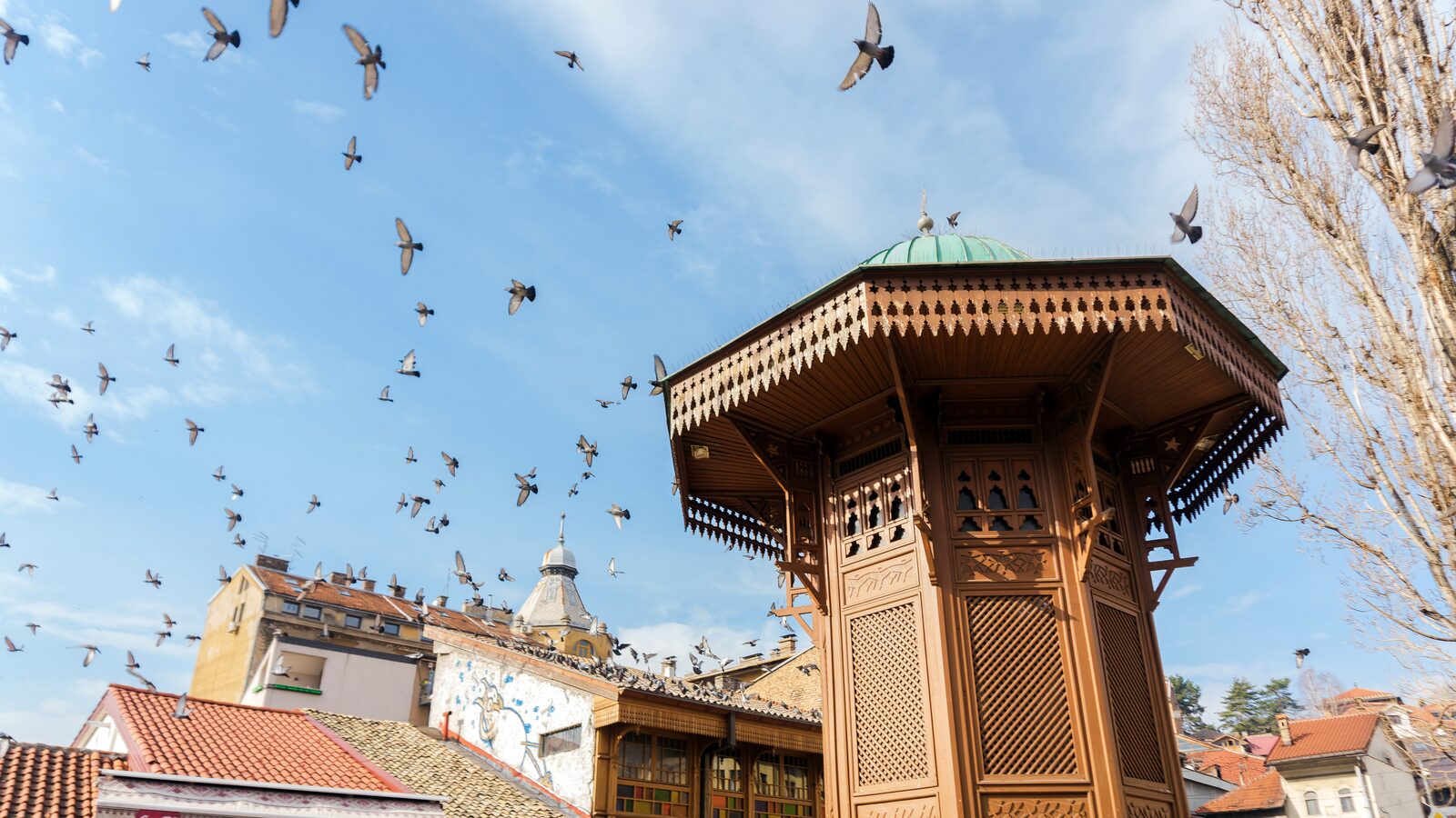Baščaršija in central Sarajevo, with the Sebilj fountain in the square and the bazaar's tiled rooftops around it.