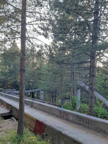 The interior surface of the Sarajevo bobsled track, layers of overpainted graffiti on scarred 1980s concrete.