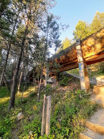 A view down the Sarajevo bobsled track from inside the chute, curves receding into the pine forest.