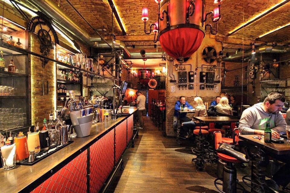 A view of the bar at Café Barometar with exposed brick and hanging fixtures.
