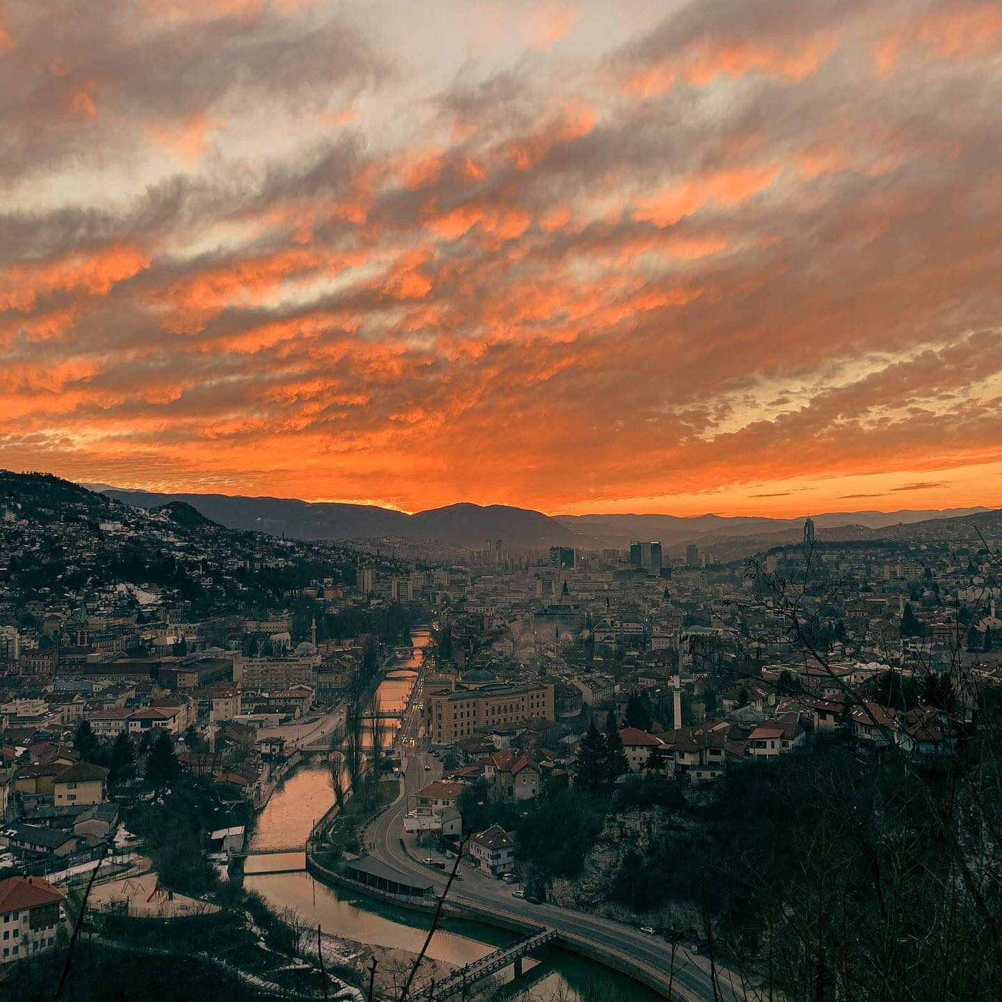 Sarajevo at sunset, seen as a panoramic view from the Caffe Kamarija terrace, the bazaar's lights coming on below.