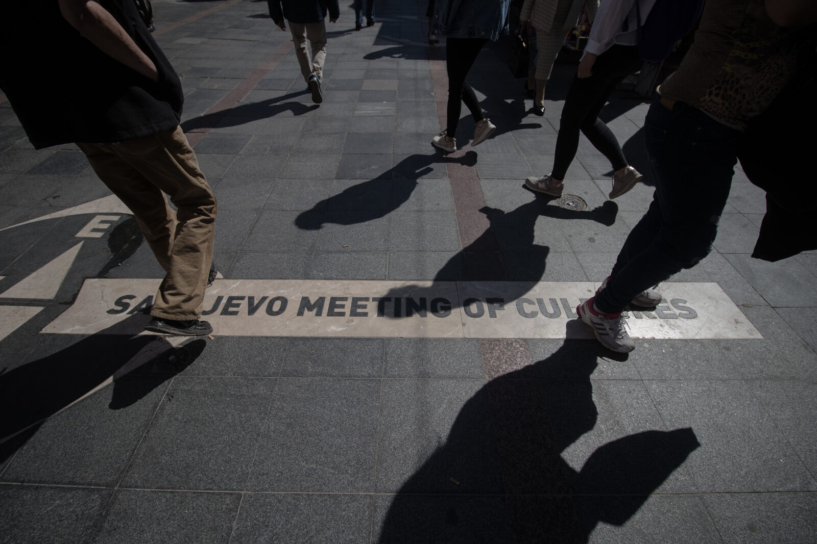 The Meeting of Cultures brass line embedded in the pavement of Ferhadija in Sarajevo, with the inscription marking the architectural boundary between the Ottoman and Habsburg quarters of the city.