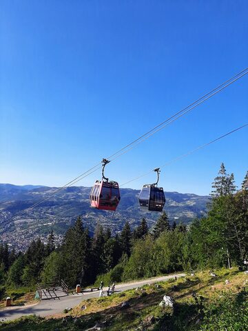 Two cabins on the Trebević line above the forest, with Sarajevo in the valley behind.