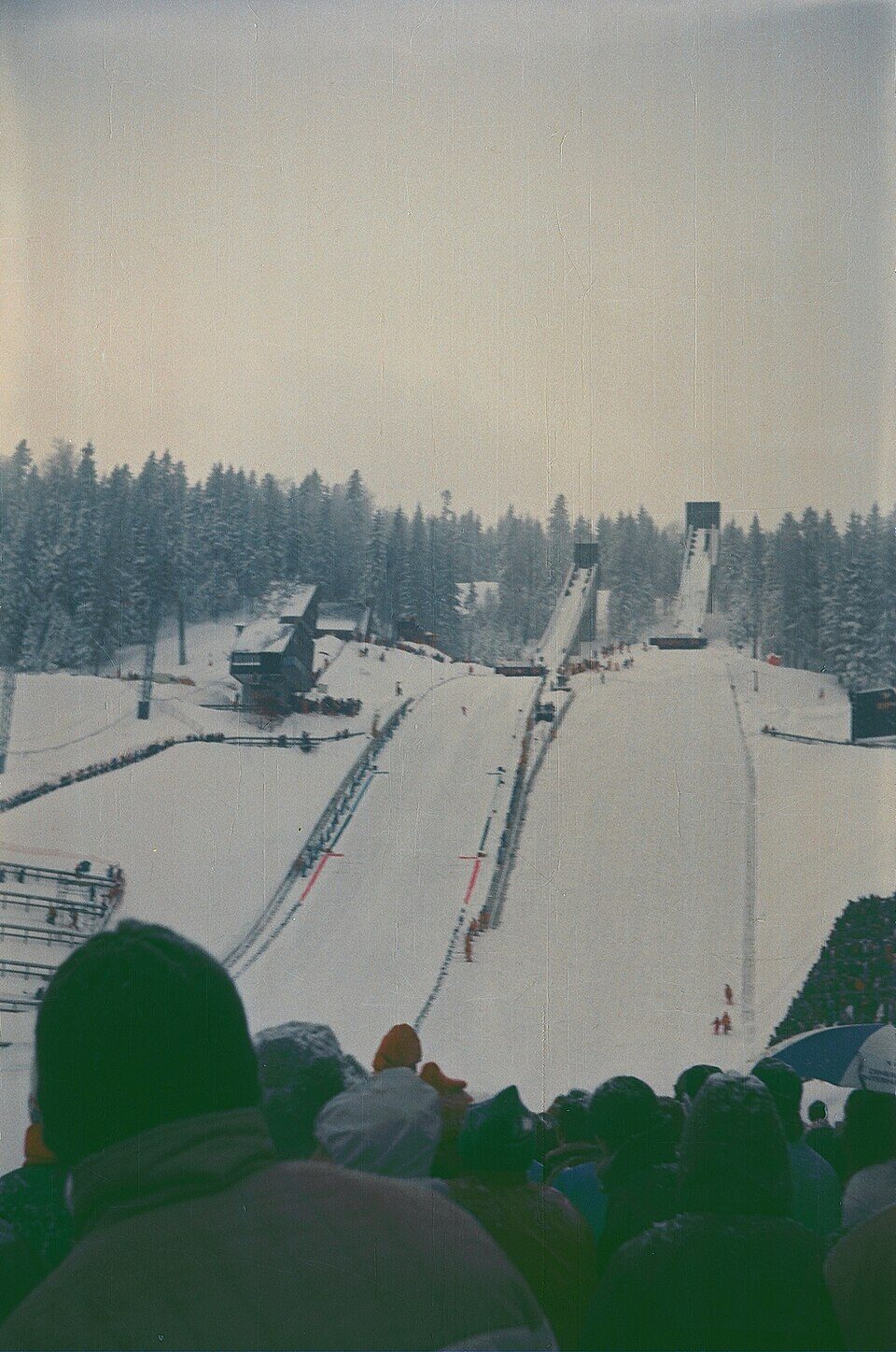 The abandoned large ski jump on Mount Igman near Sarajevo, the concrete tower and ramp overgrown and partially damaged, with mountains and forest behind.