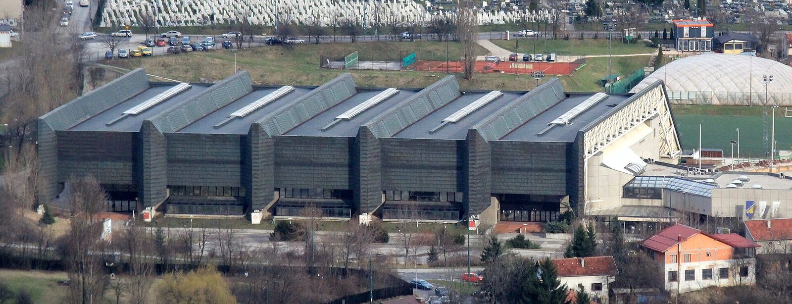 The exterior of Zetra Olympic Hall in Sarajevo, a modernist concrete sports arena with a distinctive angular roof, rebuilt after severe damage during the 1992–1995 siege.