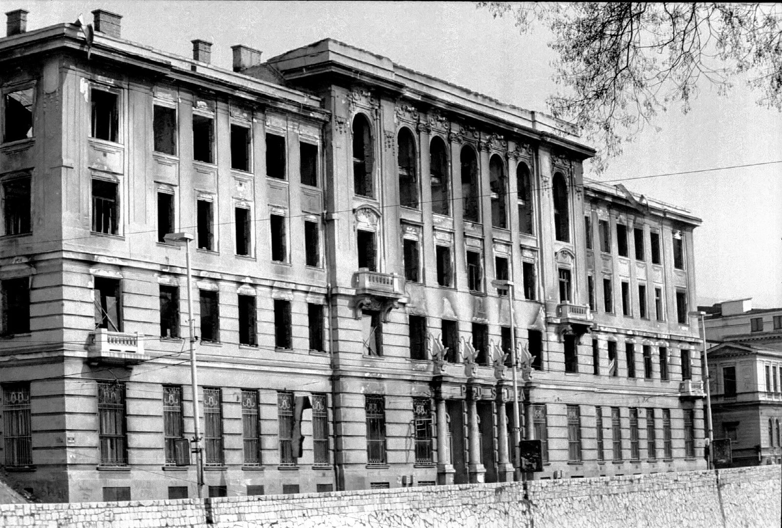 Josip Vancaš's Main Post Office in Sarajevo, gutted by incendiary shells during the 1992 siege — the fire-blackened Habsburg-era facade with upper floors destroyed.