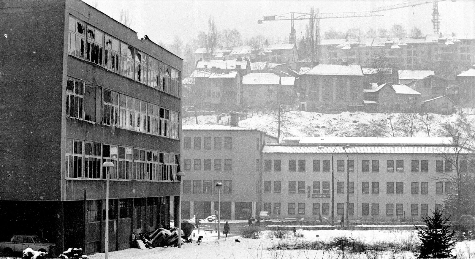 A snow-covered boulevard in Sarajevo during the 1992–1995 siege — a wide street empty of traffic, framed by damaged apartment blocks, in the winter conditions civilians moved through under sniper fire.