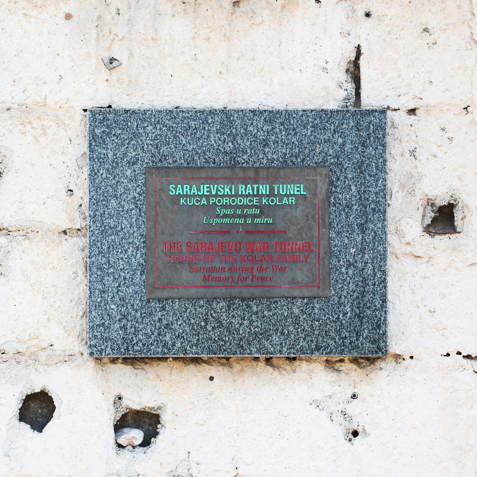 The entrance plaque to the Sarajevo War Tunnel museum, with the original tunnel mouth in the background.