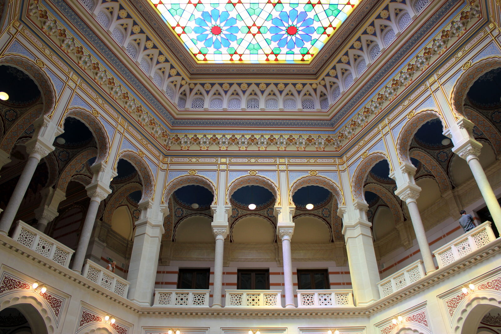 The restored atrium of Vijećnica — banded stone arches and stained glass beneath the great dome.